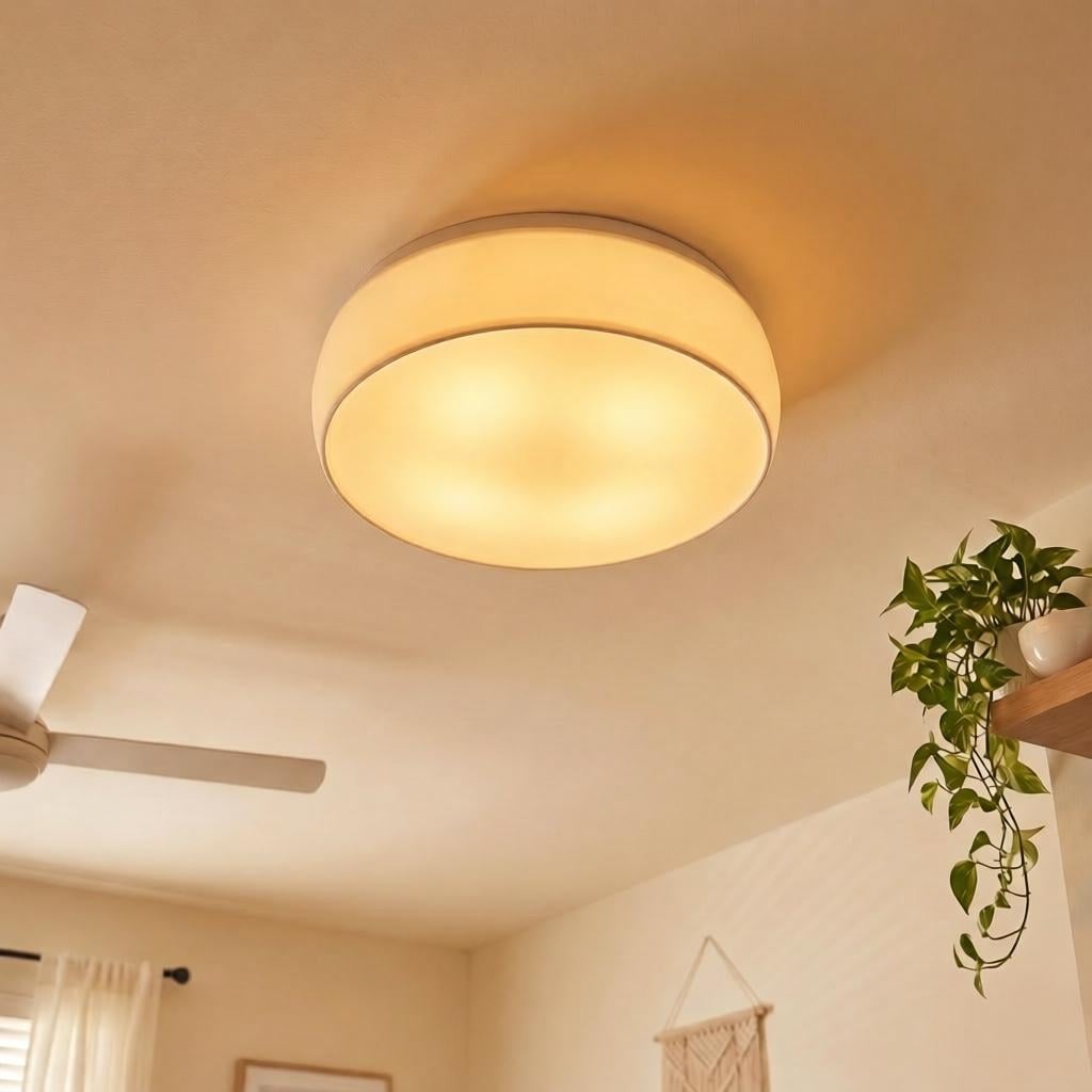Close-up of an amber Glow Dome ceiling light diffuser installed on a recessed LED light, casting a warm cozy glow in a neutral room with a ceiling fan and trailing plant.
